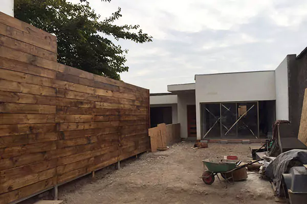 Se está construyendo una valla de madera sin terminar en el patio trasero de una casa blanca