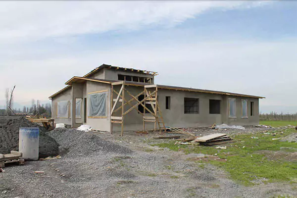 Una casa en construcción con andamios de madera, un montón de tierra y varios trozos de madera esparcidos por todos lados