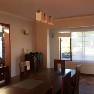 Un comedor limpio con mesa, sillas y ventana de madera