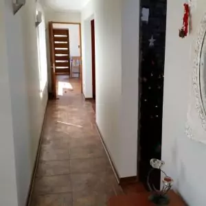 Un largo pasillo con suelos de baldosas y puertas a la derecha