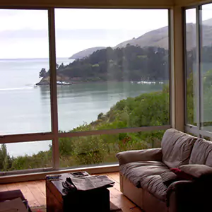 Una sala de estar con sofá, mesa de café y grandes ventanales con vista a una hermosa vista del agua