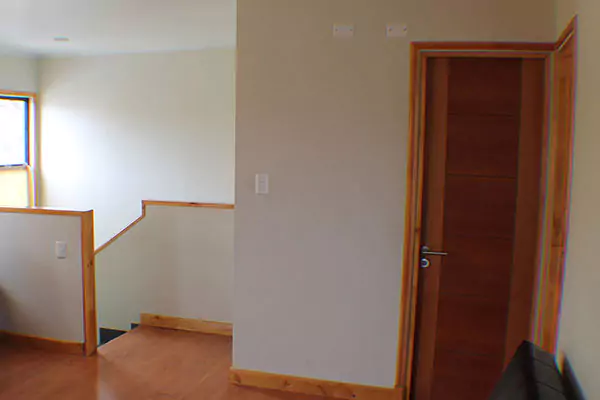 Hay una puerta abierta en una habitación con suelo de madera y paredes de colores claros