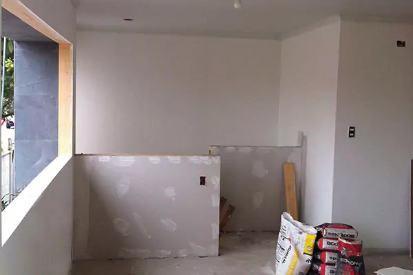 Una habitación con paredes sin terminar, una ventana y materiales de construcción